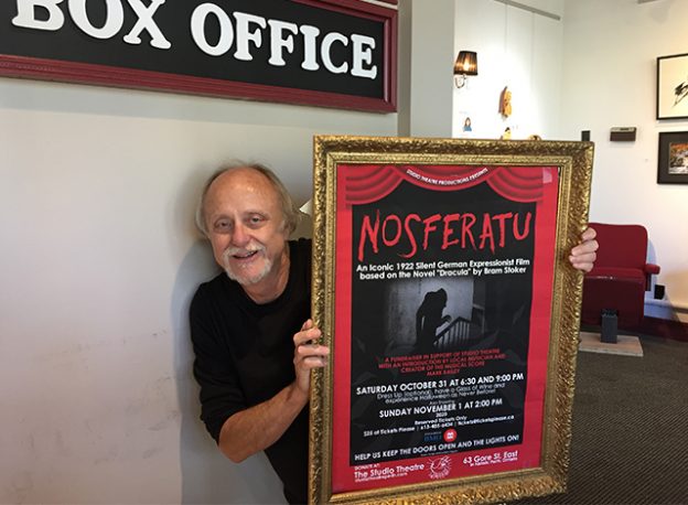 Perth musician and composer Mark Bailey holding a horror movie Nosferatu poster.