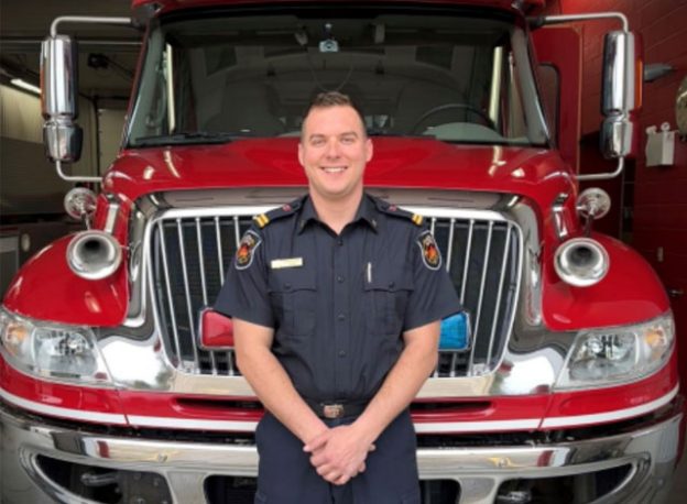 Mike Rowntree standing in front of a fire truck.