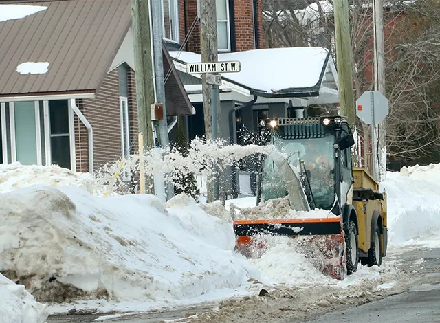 Snow plow throwing snow on a snowbank off the road.