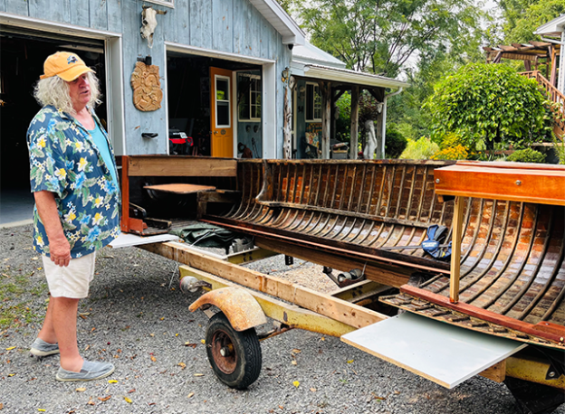 James Graham standing in front of an old boat being turning into a bar.